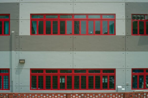 Architectural detail of a building facade featuring striking red-framed windows and geometric design.