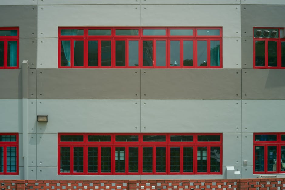 Architectural detail of a building facade featuring striking red-framed windows and geometric design.