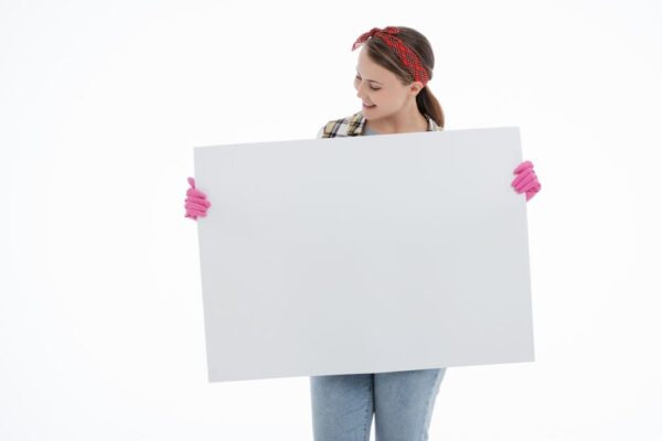 Young woman in a plaid shirt and gloves presenting a blank board with copyspace.